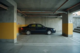 Place de parking souterrain aux dimensions insuffisantes dans un immeuble résidentiel, illustrant le manque d'espace conforme aux normes